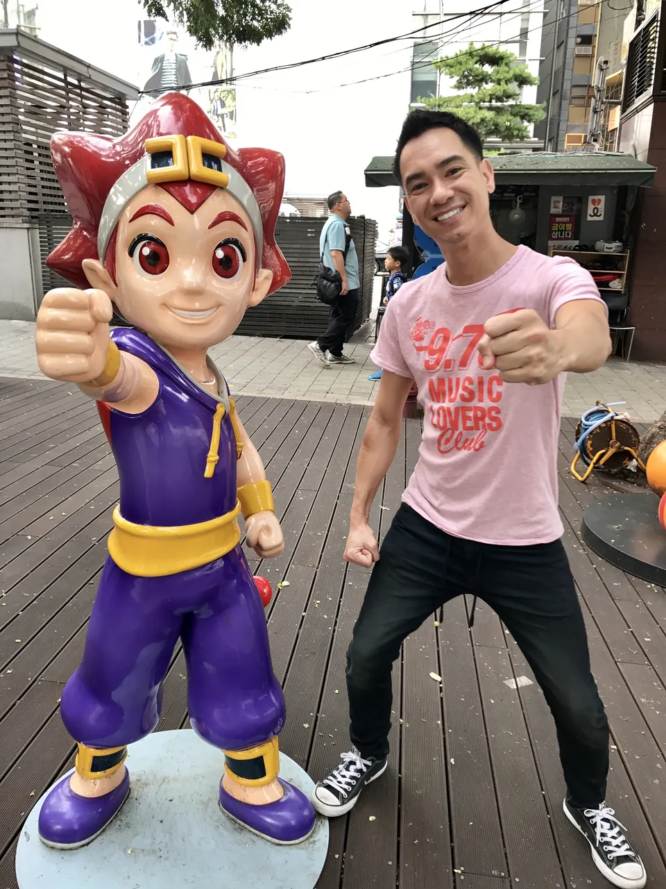 Andre smiling and matching the outstretched-fist pose of a colorful cartoon statue.